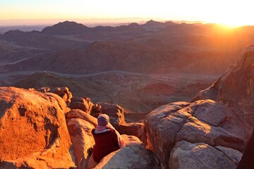 a woman watching the sunrise on the top of mountain moses in saint catherine in sinai in egypt
