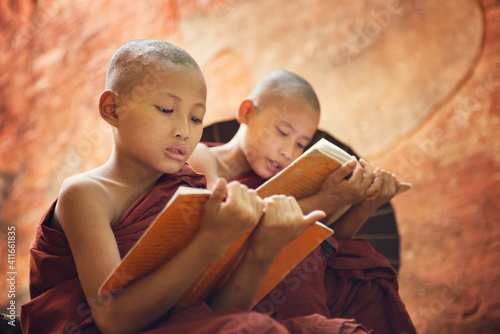 Teenage Monks Reading Books Against Wall