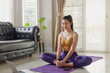 © butsaya33 - Young Asian woman practicing yoga class with group of people at home on a video conference. Fitness instructor taking online yoga classes over a video call in laptop