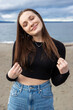 © Mat Hayward - Teenage girl outside at Alki Beach in West Seattle with a view of the Puget Sound and the city of Seattle in Washington State.