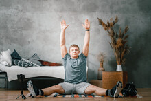 The Strong Man Goes In For Sports At Home. Cheerful Sporty Man With Blond  Hair Stretches To The Leg  And.watching Video,  Shootting  Blog  In The Bedroom