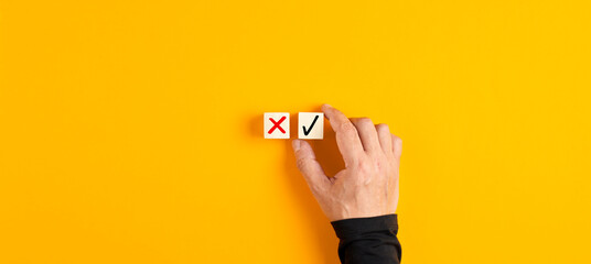 Wall Mural - right and wrong icons on wooden cubes with male hand choosing the right icon