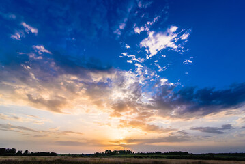 Wall Mural - summer morning landscape with colorful sunrise and sun rays in the sky with clouds over the meadow