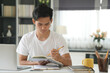 © 88studio - asian young student man entrepreneur working with computer writing note studying learning online at home. e-learning webinar meeting. social distance in covid pandemic
