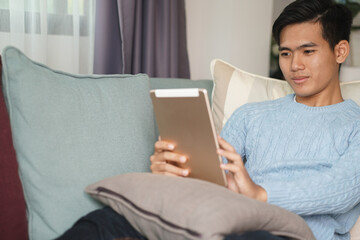 asian young student man entrepreneur working with tablet computer studying learning online at home. e-learning webinar meeting. social distance in covid pandemic