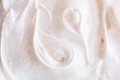 Creamy texture of white airy scrub foam with peeling particle. Cosmetic background with warm light bege hue