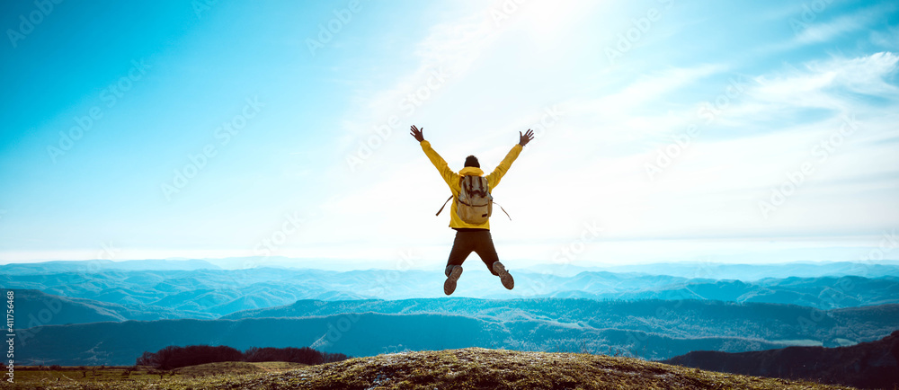 Happy man with open arms jumping on the top of mountain - Hiker with backpack celebrating success outdoor - People, success and sport concept - obrazy, fototapety, plakaty 