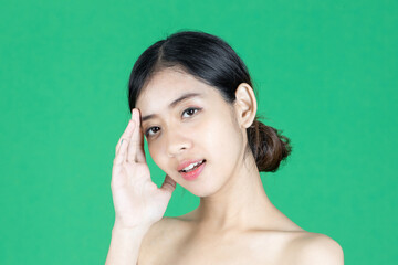 Wall Mural - Beauty young Asian woman touching her face over green isolated background. Healthy skin care concept.