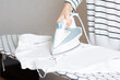 © Владислав Легір - Woman is ironing clothes. The girl holds an iron on an ironing board.