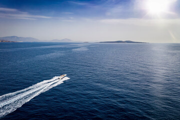 Wall Mural - aerial view of a motor yacht traveling over blue sea towards an island on the horizon