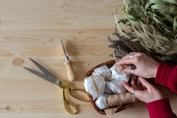 Eco flat lay with organic cosmetics, soap and shampoo, eco natural ingredients eucalyptus and lavender lying on wooden table, spa products, woman holding in hands