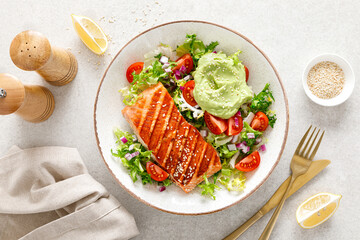 Wall Mural - Grilled salmon fish fillet and fresh green lettuce vegetable tomato salad with avocado guacamole. Top view