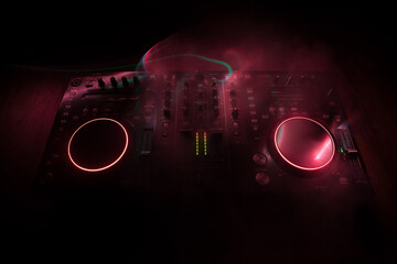 Wall Mural - DJ console deejay-mixing desk in dark with colorful light. Mixer equipment entertainment DJ station.