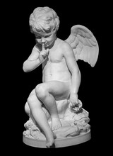 White Angel Figurine Isolated On Black Background. Cupid Sculpture. Stone Statue Of Young Cherub
