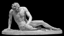 Ancient White Marble Sculpture Of Naked Dying Man Gaul. Antique Classic Statue Of Soldier Isolated On Black. Stone Wounded Male Figure