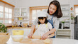© tirachard - Happy smiling young Asian Japanese family with preschool kids have fun cooking baking pastry or pie for breakfast meal in modern kitchen home in the morning. Doing bakery knead dough and bake cookies.