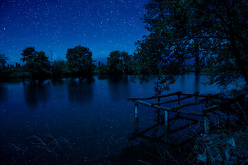 Wall Mural - milky way over a lake at summer night with clear skies under moonlight.