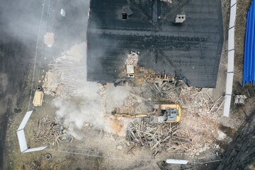 Yellow excavator destroys building. Heavy duty machine is demolishing a brick building. Demolition of the building . Demolition construction work aerial drone photo