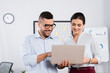 © LIGHTFIELD STUDIOS - business people looking at laptop while smiling in office