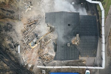 Yellow excavator destroys building. Heavy duty machine is demolishing a brick building. Demolition of the building . Demolition construction work aerial drone photo