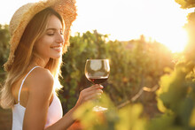 Beautiful Young Woman With Glass Of Wine In Vineyard On Sunny Day