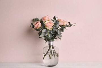 Poster - Vase with bouquet of beautiful roses on white wooden table near beige wall