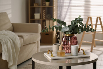 Bunch of eucalyptus branches and oil diffuser on table in living room. Interior design