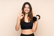 © luismolinero - Young sport woman making weightlifting isolated on beige background showing an ok sign with fingers
