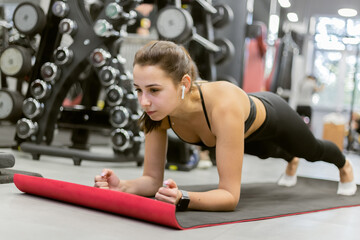 Fitness girl practicing plank exercise in modern gym