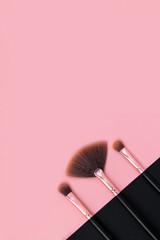 Wall Mural - A set of professional makeup brushes in a row on a pink and dark background. Tools for make-up artist in black and gold color. Vertically concept for cosmetics, beauty concept, skin care. Copy space