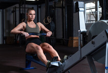Young Strong Fit Sweaty Powerful Attractive Muscular Woman With Big Muscles Doing Hard Core Row Heavy Training Workout On Indoor Rower At The Gym Real People Rowing Exercise