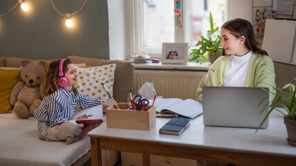 Wall Mural - Sisters schoolgirls learning online indoors at home, coronavirus concept.