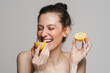 © Drobot Dean - Joyful half-naked woman laughing while eating lemon