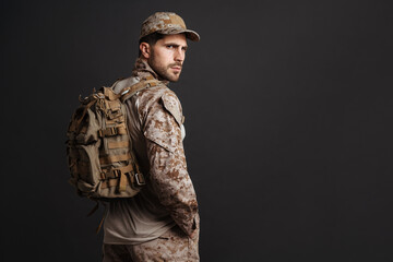 Canvas Print - Confident masculine military man in uniform posing with backpack