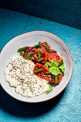 Delicious Korean tofu. Fried tofu in a spicy glaze, sprinkled with green onions and coriander. Served on a beautiful white plate with borders and chopsticks. And it all fits nicely with the blue backg