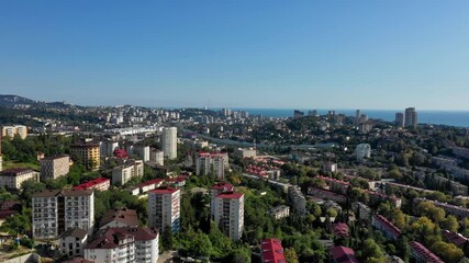 Wall Mural -  Aerial Drone shot with an amazing view Sochi. Aerial view. Cityscape. Shooting from above panorama of amazing touristic city resort with mountain and sea.