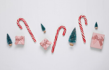 Wall Mural - Christmas striped candy canes, gift boxes and mini Christmas trees on white background. New year, xmas background