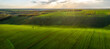Aerial view of beautiful countryside with green rolling field in golden hour before sunset..
