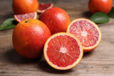 Fototapeta Kuchnia - Whole and cut red oranges on wooden table, closeup