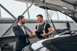 © HBS - Handsome businessman and auto service mechanic are discussing the work and shaking hands.