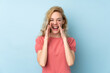 © luismolinero - Young blonde woman isolated on blue background shouting with mouth wide open