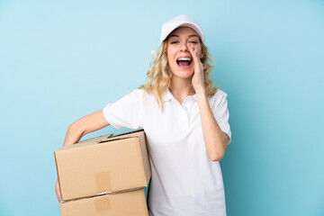 Poster - Young delivery woman isolated on blue background shouting with mouth wide open