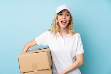 Canvas Print - Young delivery woman isolated on blue background with surprise facial expression