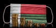Medical mask with the flag of Madagascar behind some shrinking stacks of various coins.(series)