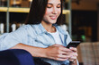 © foxyburrow - Attractive business woman sits at table and talks on mobile phone, negotiates on the phone. Beautiful brunette girl uses gadgets for work. Online training, remote work from home