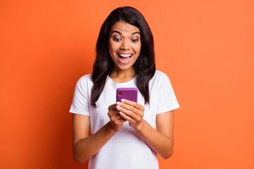 Poster - Photo of impressed girl hold telephone wear white t-shirt isolated on orange color background