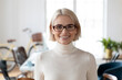 © fizkes - Head shot of happy professional employee posing in modern office. Profile picture of small business owner woman wearing glasses smiling at camera. Corporate portrait, female leadership concept