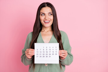 Photo of lady show calendar look empty space wear green cardigan isolated pastel pink color background