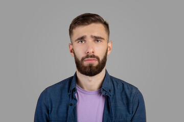 Millennial hipster guy feeling sad, lonely or depressed on grey studio background