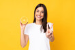 © luismolinero - Young caucasian woman holding an orange isolated on yellow background smiling and showing victory sign